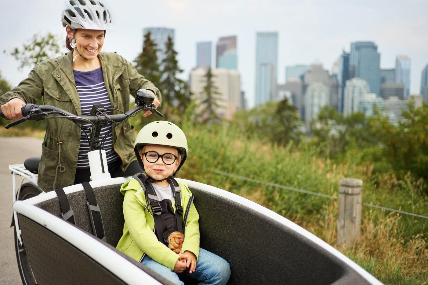 Smiling mom and riding a cargo bike with her young son